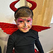 Rose participe au concours pour gagner de l'argent avec cette photo : child, face_paint, costume, devil_horns, red_wings, smiling, black_shirt, red_skirt, indoor, portrait, cute, happy, headband, makeup, person, holiday, festive, party, young, celebration