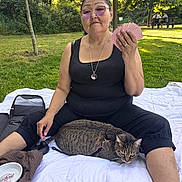 Chipinette participe au concours pour gagner de l'argent avec cette photo : woman, cat, playing_cards, park, blanket, glasses, trees, grass, outdoor, sitting, leisure, pet, harness, picnic, people, bench, sunlight, casual_clothing, relaxation, nature