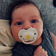 Leilani joined the competition — help win amazing prizes! baby, infant, pacifier, blue_eyes, close_up, cute, hand, dark_hair, sleepwear, portrait, skin, face, expression, indoors, cozy, soft_texture, child, newborn, comfort, resting