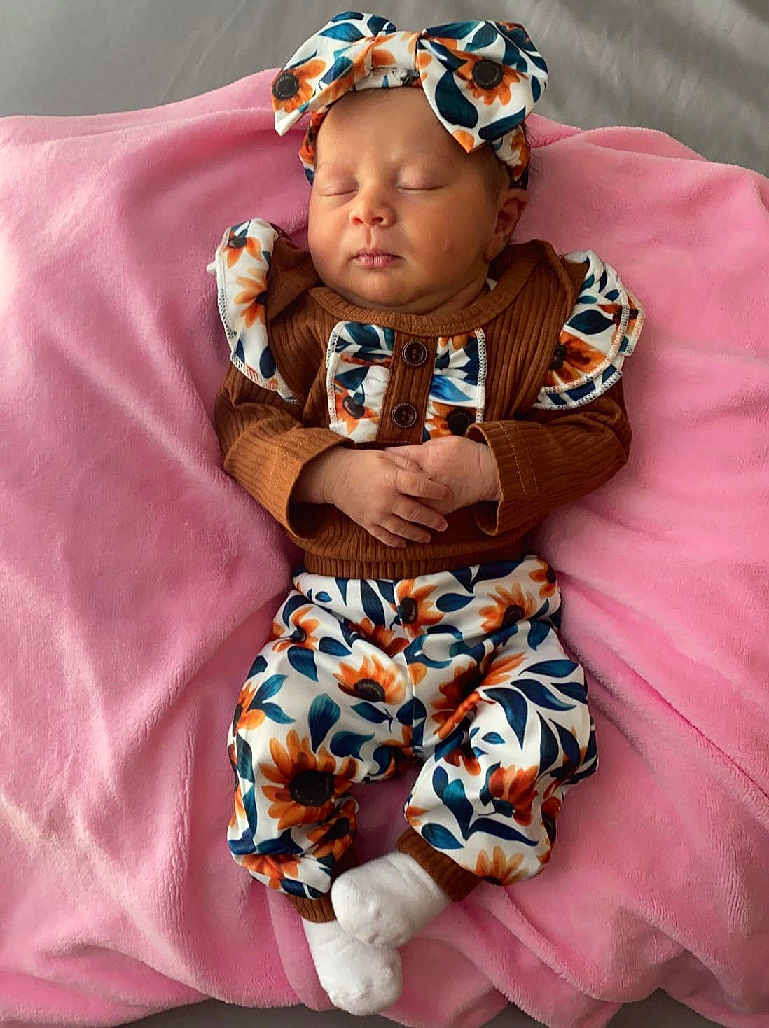 Jazlynn is registered to the contest to win money with this photo: arm, baby, baby_products, baby_toddler_clothing, child, eye, fashion_accessory, happy, head, headband, linens, magenta, pattern, person, personal_protective_equipment, pink, purple, sitting, sleeve, textile
