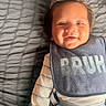 Jesus is registered to the contest to win money with this photo: baby, smile, bib, clothing, striped_shirt, gray_blanket, hair, happy, infant, portrait, lying_down, cute, child, face, toddler, textile, fabric, indoor, person, soft