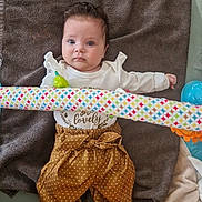 Agathe a rejoint le concours — aidez-le/la à gagner de superbes lots ! baby, infant, towel, toy, play_gym, colorful, polka_dot, pants, white_top, socks, floor, curious, child, indoor, soft_toy, playtime, bright_eyes, cute, lying_down, young_child