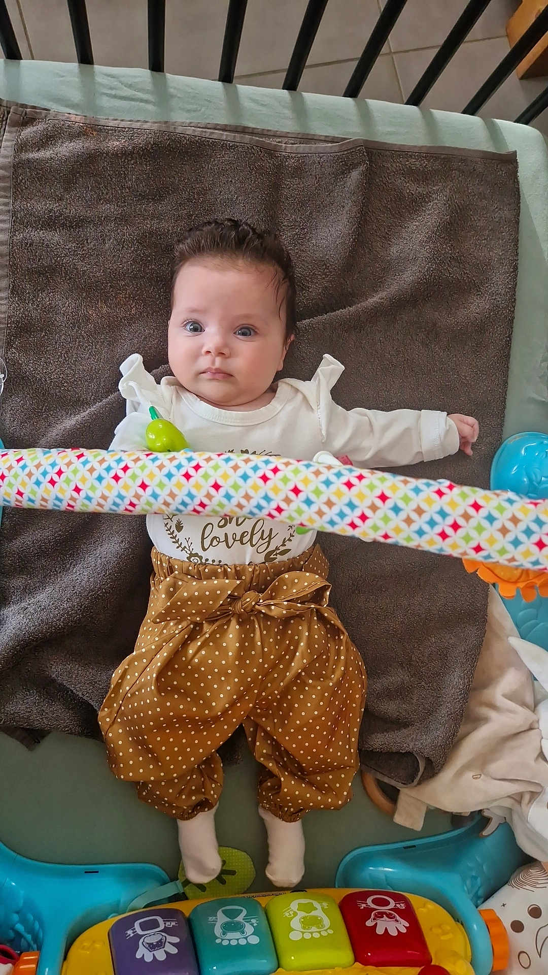 Agathe a rejoint le concours — aidez-le/la à gagner de superbes lots ! baby, infant, towel, toy, play_gym, colorful, polka_dot, pants, white_top, socks, floor, curious, child, indoor, soft_toy, playtime, bright_eyes, cute, lying_down, young_child