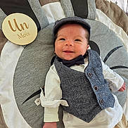 Lowen participe au concours pour gagner de l'argent avec cette photo : baby, infant, smiling, face, vest, bow_tie, cap, play_mat, wooden_plaque, clothing, happy, lying_down, one_month, cute, child, indoor, portrait, fabric, buttoned_vest, infant_boy