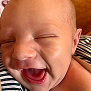 Nash is registered to the contest to win money with this photo: baby, infant, newborn, smiling, laughing, mouth_open, tongue, close_up, face, forehead, cheek, ear, eyes_closed, skin, striped_onesie, fabric, portrait, indoors, warm_tones, candid