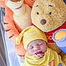 baby, newborn, sleeping, plush_toy, stuffed_animal, winnie_the_pooh, tigger, yellow_clothing, crib, hat, cute, child, soft_toy, indoor, infant, resting, smiling_toy, snug, cozy, portrait