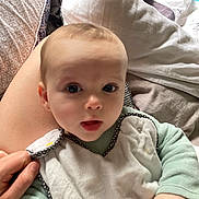 Lucien participe au concours pour gagner de l'argent avec cette photo : baby, infant, child, face, hand, bib, clothing, bed, blanket, pillow, person, indoor, cute, expression, young, skin, head, eyes, mouth, comfort