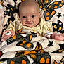 baby, blanket, butterfly_pattern, star_pattern, plush_toy, smiling, face, infant, cute, cozy, child, soft_texture, warm, lying_down, indoors, person, comfort, happy, wearing_clothes, pink