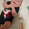 baby, infant, smiling, black_clothing, onesie, blanket, star_pattern, wooden_tie, months_marker, hand_clasp, lying_down, cute, child, face, portrait, indoors, happy, young_child, person, baby_boy