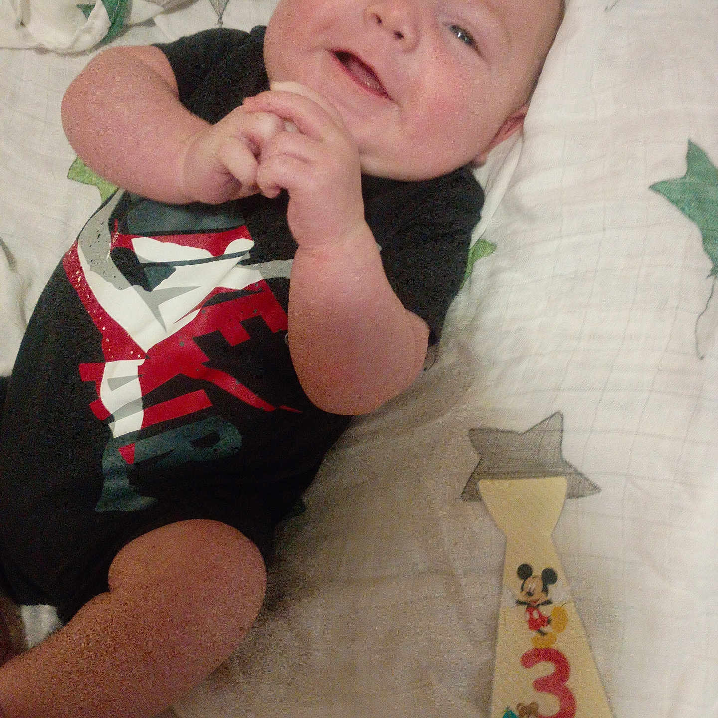 Hudson joined the competition — help win amazing prizes! baby, infant, smiling, black_clothing, onesie, blanket, star_pattern, wooden_tie, months_marker, hand_clasp, lying_down, cute, child, face, portrait, indoors, happy, young_child, person, baby_boy