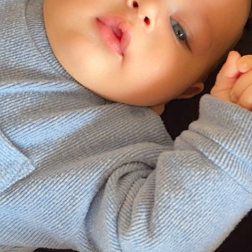 Naor a rejoint le concours — aidez-le/la à gagner de superbes lots ! adult, baby, blanket, blue_sweater, cheeks, close_up, cozy, cuddling, eyes, face, hand, indoor, infant, knitwear, lips, mobile_status_bar, peek, portrait, skin, soft_light