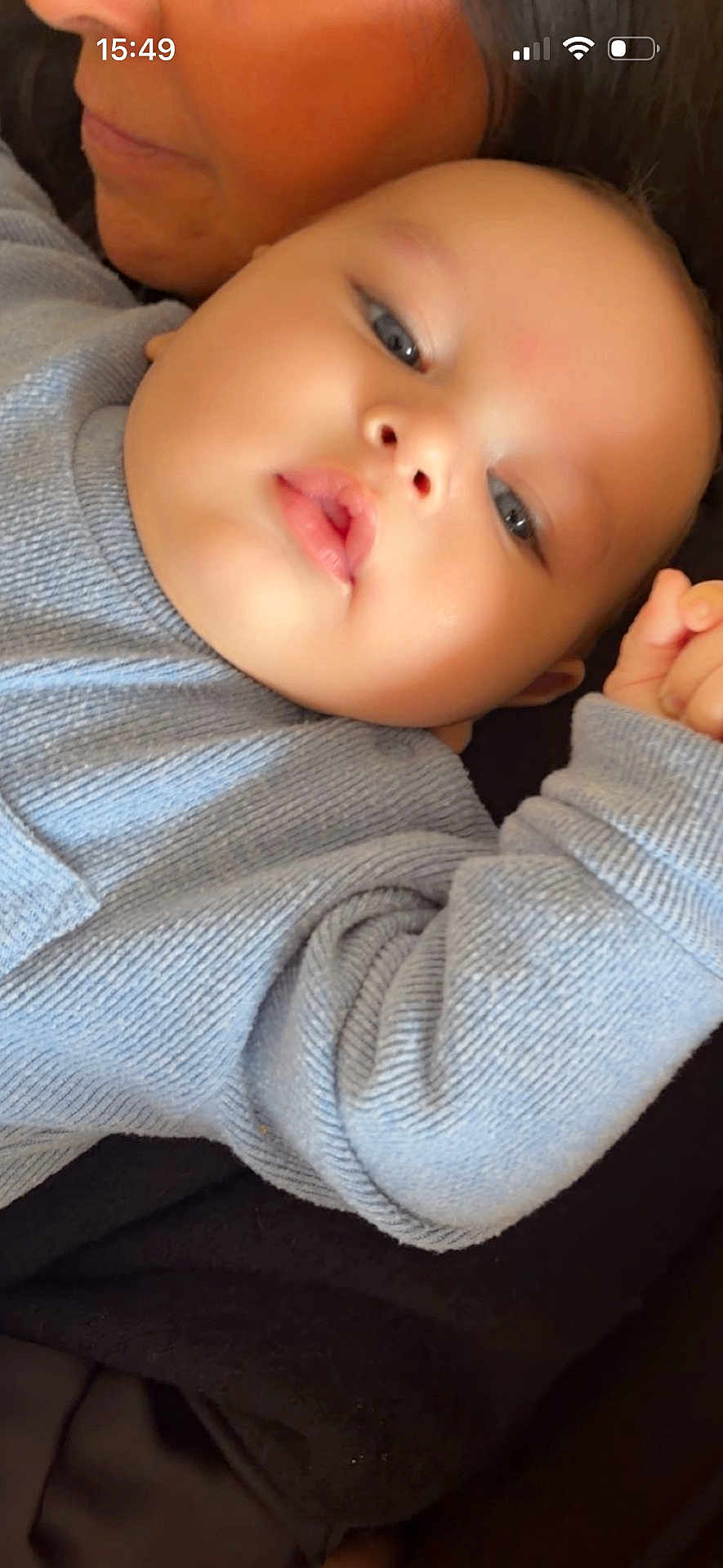 Naor a rejoint le concours — aidez-le/la à gagner de superbes lots ! baby, infant, adult, face, close_up, portrait, blue_sweater, knitwear, cheeks, lips, eyes, hand, cuddling, blanket, cozy, indoor, soft_light, skin, mobile_status_bar, peek