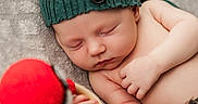 Eryk is registered to the contest to win money with this photo: baby, blanket, button, child, comfort, cozy, cute, hand, hat, indoors, infant, knit, peaceful, portrait, red_toy, resting, skin, sleeping, soft_texture, warm