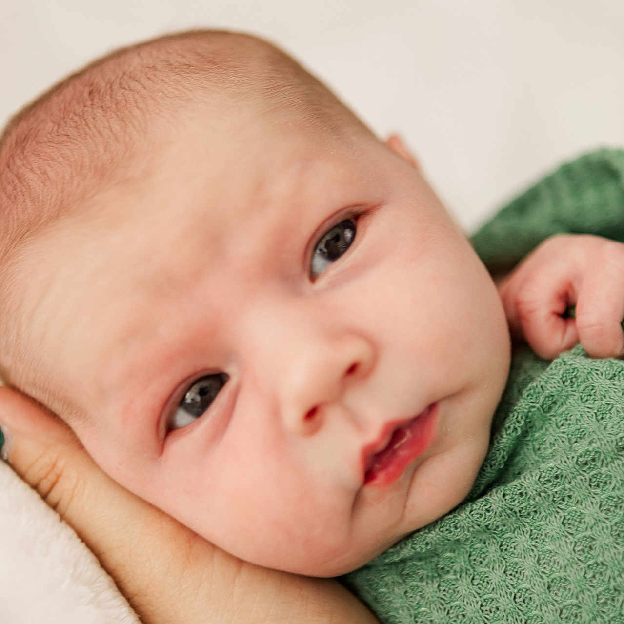 Eryk is registered to the contest to win money with this photo: baby, infant, closeup, face, hand, green_blanket, texture, skin, portrait, expression, resting, newborn, cute, young_child, human, soft_light, indoor, peaceful, curious, tiny_fingers