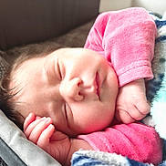 Mahona participe au concours pour gagner de l'argent avec cette photo : baby, sleeping, blanket, pink_clothing, infant, face, hand, cozy, resting, soft_light, cute, peaceful, newborn, skin, fingers, portrait, closeup, indoors, child, relaxation