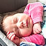 baby, sleeping, blanket, pink_clothing, infant, face, hand, cozy, resting, soft_light, cute, peaceful, newborn, skin, fingers, portrait, closeup, indoors, child, relaxation