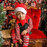 éden participe au concours pour gagner de l'argent avec cette photo : child, christmas, holiday, elf_costume, red_hat, striped_clothing, red_chair, wooden_floor, nutcracker, christmas_tree, decorations, gift_boxes, festive, boots, toy, holiday_season, portrait, indoor, smiling, cute