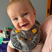 Lyrik joined the competition — help win amazing prizes! baby, infant, smile, blue_eyes, bib, lion_bib, mohawk, hair_spike, cheeks, hand, adult_hand, holding, portrait, close_up, indoor, bottle, door_frame, pink_sweater, happy, clothing