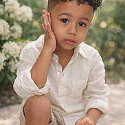 Solann a rejoint le concours — aidez-le/la à gagner de superbes lots ! child, boy, curly_hair, outdoor, nature, greenery, flower, portrait, casual_clothing, white_shirt, shorts, sitting, thoughtful, young, daylight, skin, face, hand, natural_light, expression