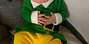 Kaylen joined the competition — help win amazing prizes! baby, sleeping, elf_costume, green_clothing, yellow_pants, hat, couch, blanket, infant, hands, closed_eyes, indoor, soft_texture, cute, holiday, festive, child, portrait, relaxation, cozy