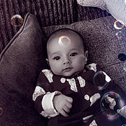 Kaylen joined the competition — help win amazing prizes! baby, infant, couch, pillow, onesie, cloud_pattern, bubbles, indoor, soft_lighting, portrait, child, cute, cozy, relaxed, smiling, furniture, closeup, home, comfort, playful