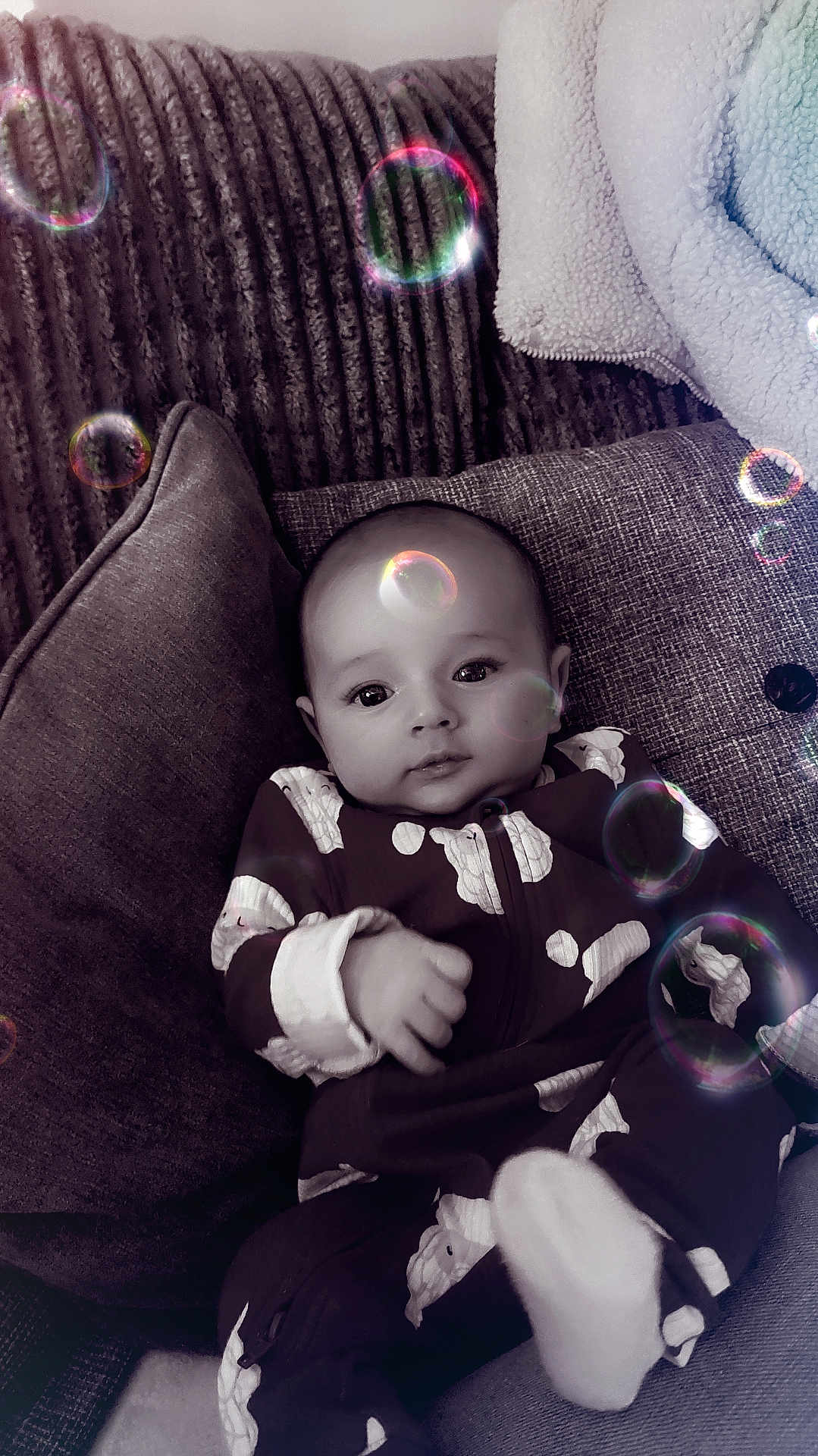 Kaylen joined the competition — help win amazing prizes! baby, infant, couch, pillow, onesie, cloud_pattern, bubbles, indoor, soft_lighting, portrait, child, cute, cozy, relaxed, smiling, furniture, closeup, home, comfort, playful