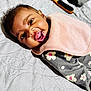 Na'Kyah is registered to the contest to win money with this photo: baby, infant, smiling, face, mouth_open, bib, clothing, floral_pattern, lying_down, quilted_bedspread, happy, child, cute, skin, head, eyes, mouth, expression, indoor, person