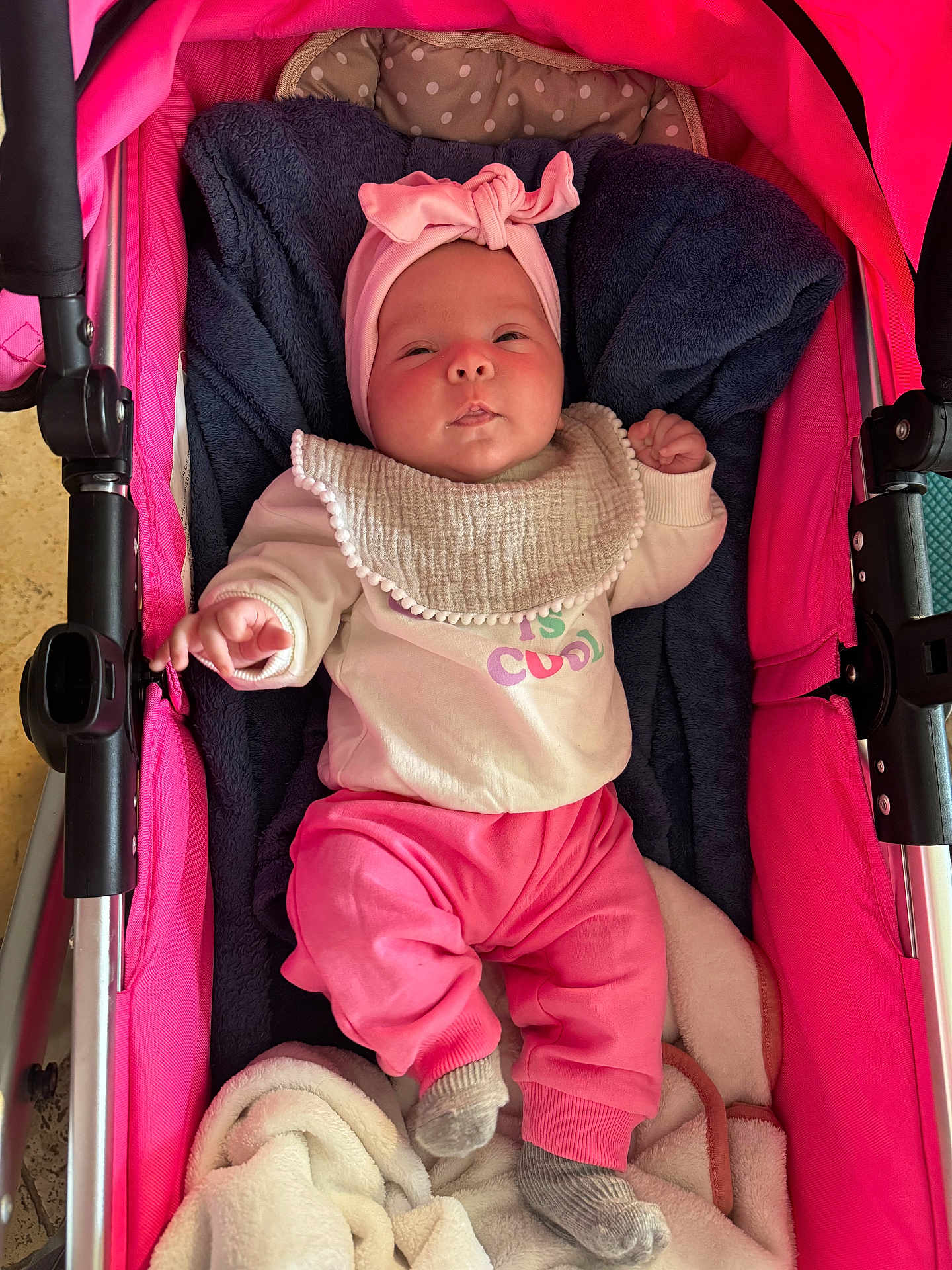 Mya a rejoint le concours — aidez-le/la à gagner de superbes lots ! baby, infant, stroller, pink_clothing, headband, bib, blanket, socks, face, person, child, cute, indoor, portrait, baby_girl, baby_wear, fabric, soft, seat, resting