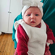 Elyana participe au concours pour gagner de l'argent avec cette photo : baby, blue_eyes, checked_dress, child, cozy_clothing, cute, face, hand, headwear, indoor, infant, looking_at_camera, person_holding, portrait, red_sweater, wardrobe, warm_lighting, white_bow, white_vest, wooden_floor