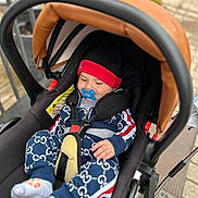 Jayden participe au concours pour gagner de l'argent avec cette photo : baby, baby_clothes, baby_seat, black, canopy, child, clothing, comfort, cute, footwear, hat, infant, jacket, outdoor, pacifier, red, safety_harness, seatbelt, socks, stroller