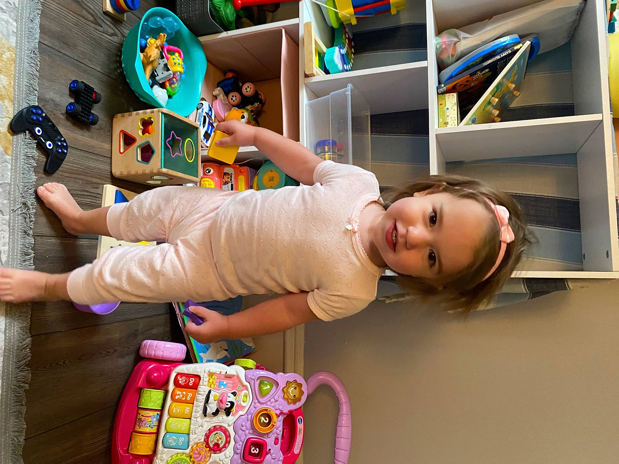 Caleigh is registered to the contest to win money with this photo: baby, baby_products, baby_toddler_clothing, baby_toys, child, flooring, fun, happy, human_leg, joy, luggage_and_bags, person, play, room, shelf, smile, snapshot, sock, t_shirt, tire