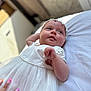 Zaïna participe au concours pour gagner de l'argent avec cette photo : baby, infant, white_dress, headband, flower, hand, nails, bed, soft_surface, portrait, cute, child, resting, gazing, indoors, person, skin, expression, young, tender_moment