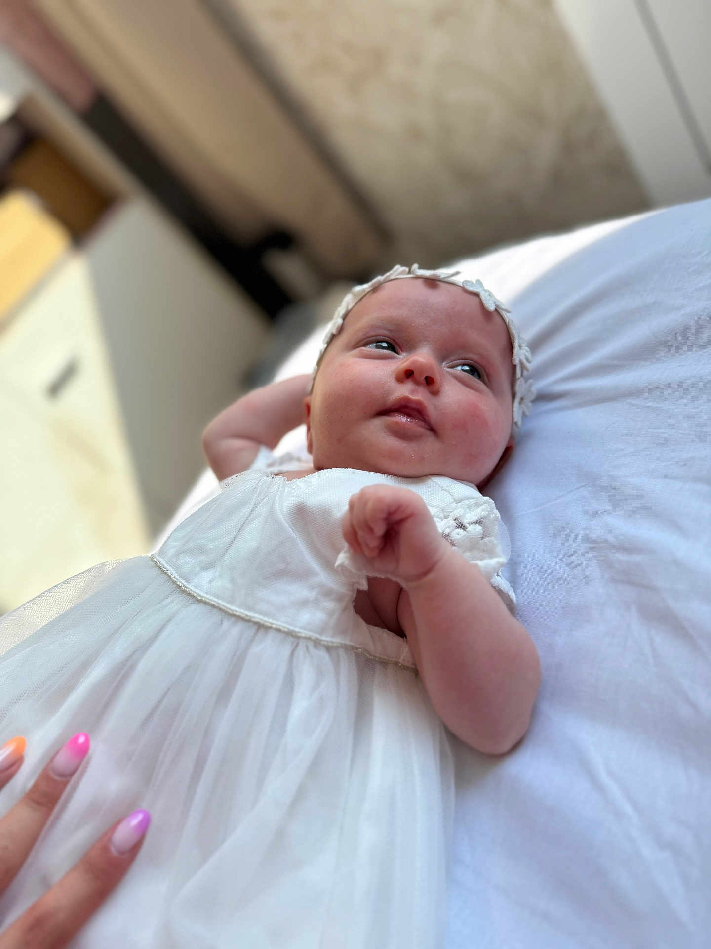 Zaïna participe au concours pour gagner de l'argent avec cette photo : baby, infant, white_dress, headband, flower, hand, nails, bed, soft_surface, portrait, cute, child, resting, gazing, indoors, person, skin, expression, young, tender_moment