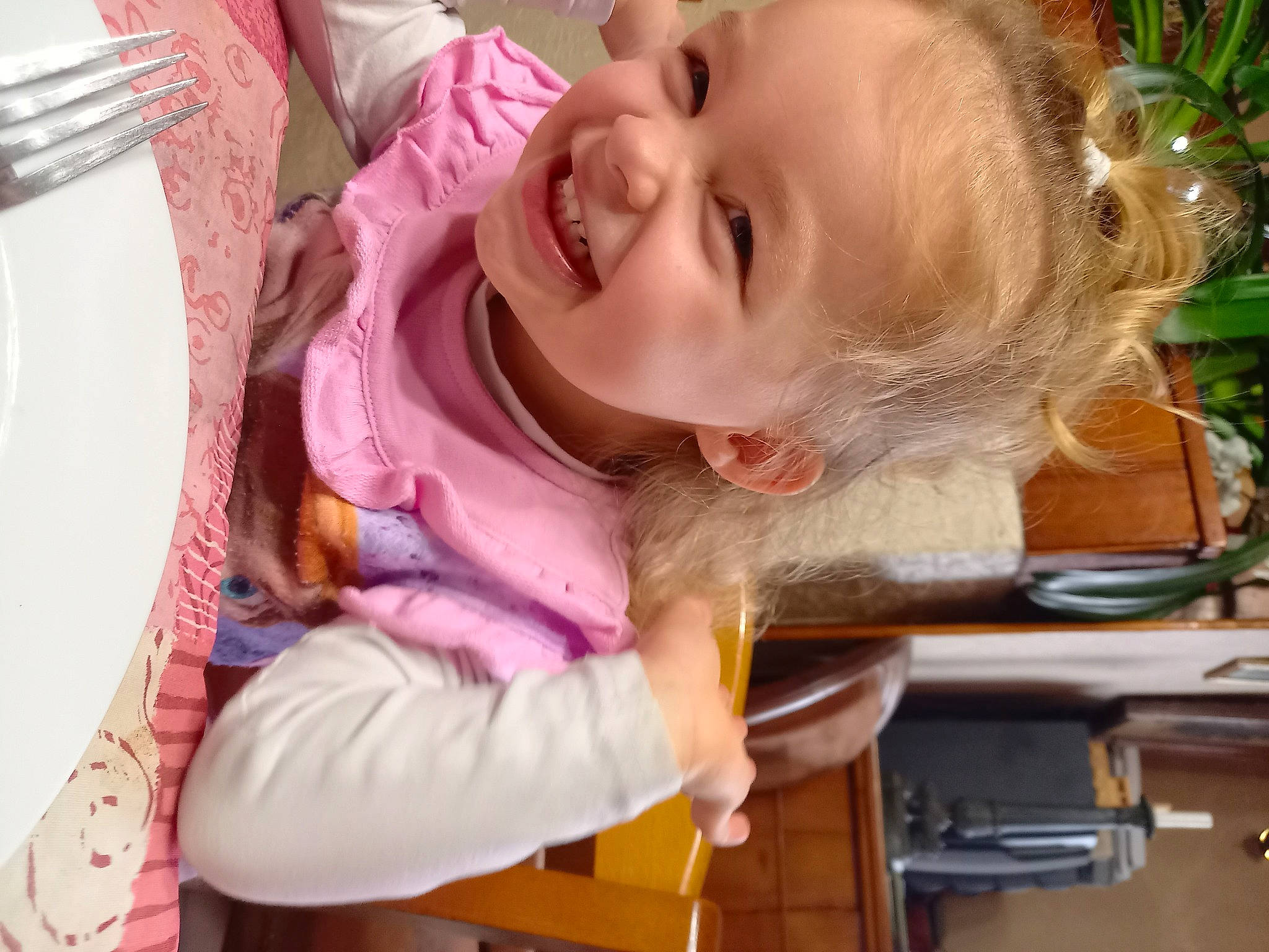 Inaya participe au concours pour gagner de l'argent avec cette photo : baby, baby_laughing, baby_toddler_clothing, cheek, child, cutlery, dishware, flowerpot, fork, household_silver, houseplant, joy, kitchen_utensil, laugh, mouth, person, plate, serveware, tablecloth, toddler