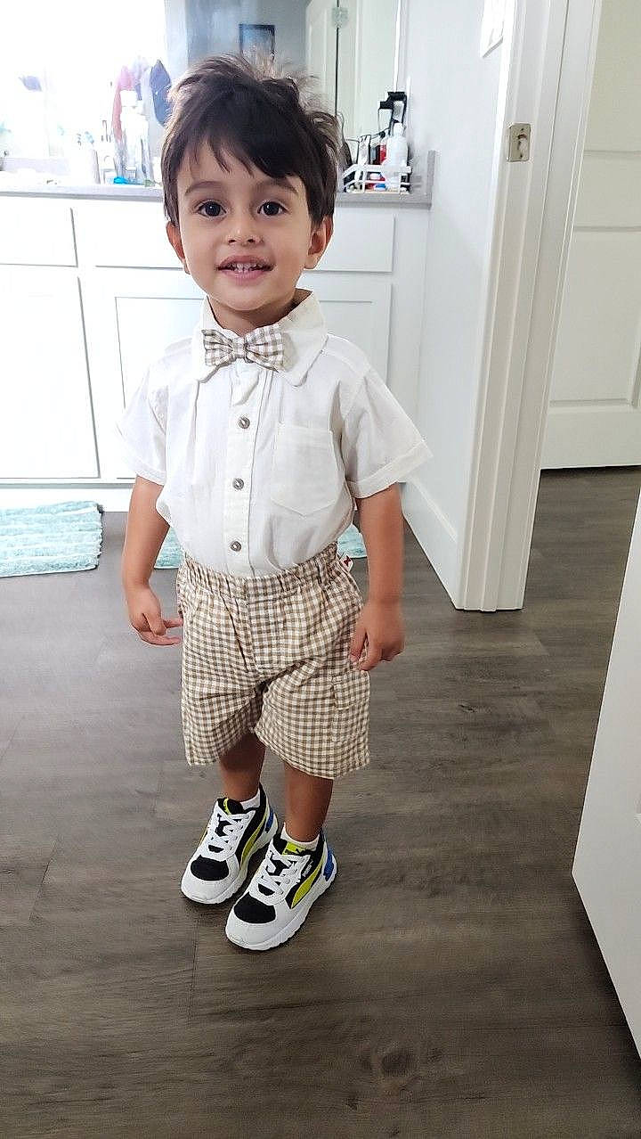 Adrian is registered to the contest to win money with this photo: baby_toddler_clothing, cabinetry, child, collar, door, dress_shirt, fashion_design, flooring, grey, happy, joy, knee, pattern, person, plaid, room, sleeve, sock, standing, t_shirt