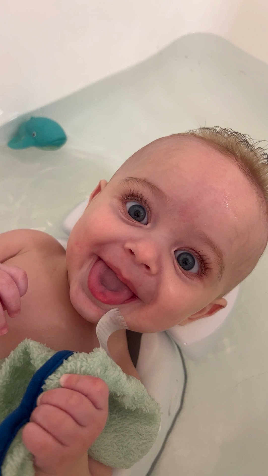 Reese joined the competition — help win amazing prizes! baby, infant, child, bathtub, bath, water, towel, blue_eyes, smiling, tongue_out, eyelashes, hand, head, close_up, bath_toy, rubber_whale, happy, bathroom, skin, portrait