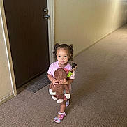 Amia Rose is registered to the contest to win money with this photo: child, toddler, toy, plush_monkey, hallway, carpet, door, door_number, pink_shirt, sandals, curly_hair, pigtails, person, indoor, standing, holding, expression, light, wall, mat