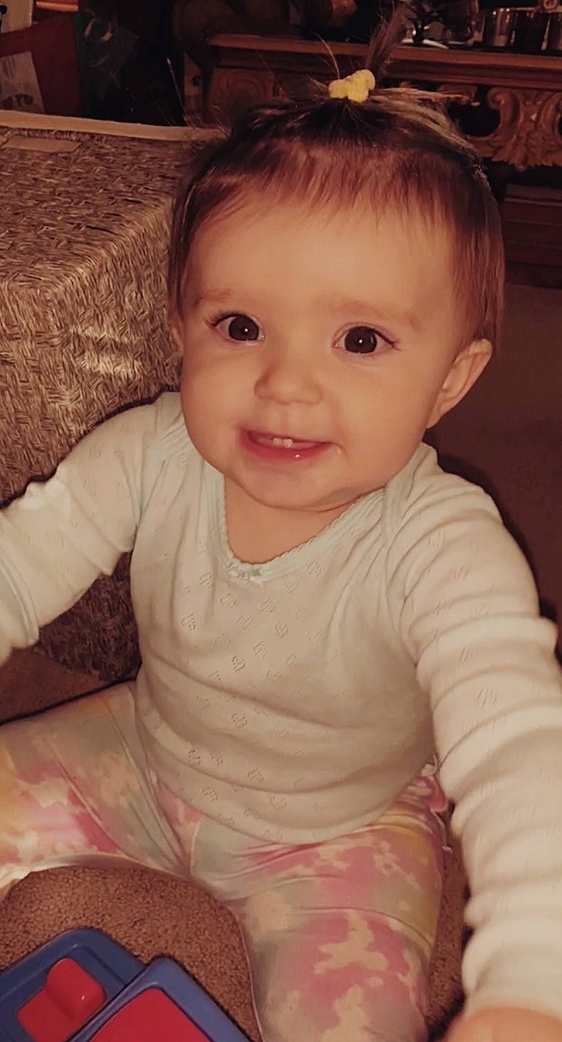 Indie is registered to the contest to win money with this photo: baby, baby_toddler_clothing, cheek, child, comfort, ear, eye, eyebrow, forehead, hair_accessory, head, home_accessories, iris, joy, linens, mouth, nose, person, sitting, skin