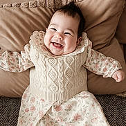 Milaya participe au concours pour gagner de l'argent avec cette photo : baby, smiling, infant, cushion, knitwear, floral_dress, happy, cute, portrait, lying_down, indoors, cozy, child, face, clothing, person, soft_texture, head, expression, warm