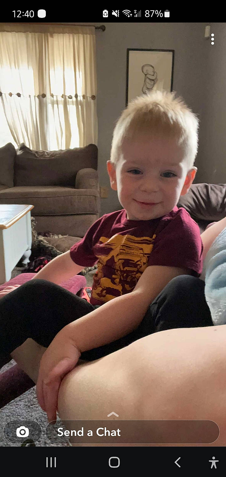 Clint is registered to the contest to win money with this photo: baby_toddler_clothing, comfort, couch, curtain, finger, flooring, hair, happy, head, human_body, joint, joy, knee, lap, living_room, mouth, person, shoulder, skin, smile