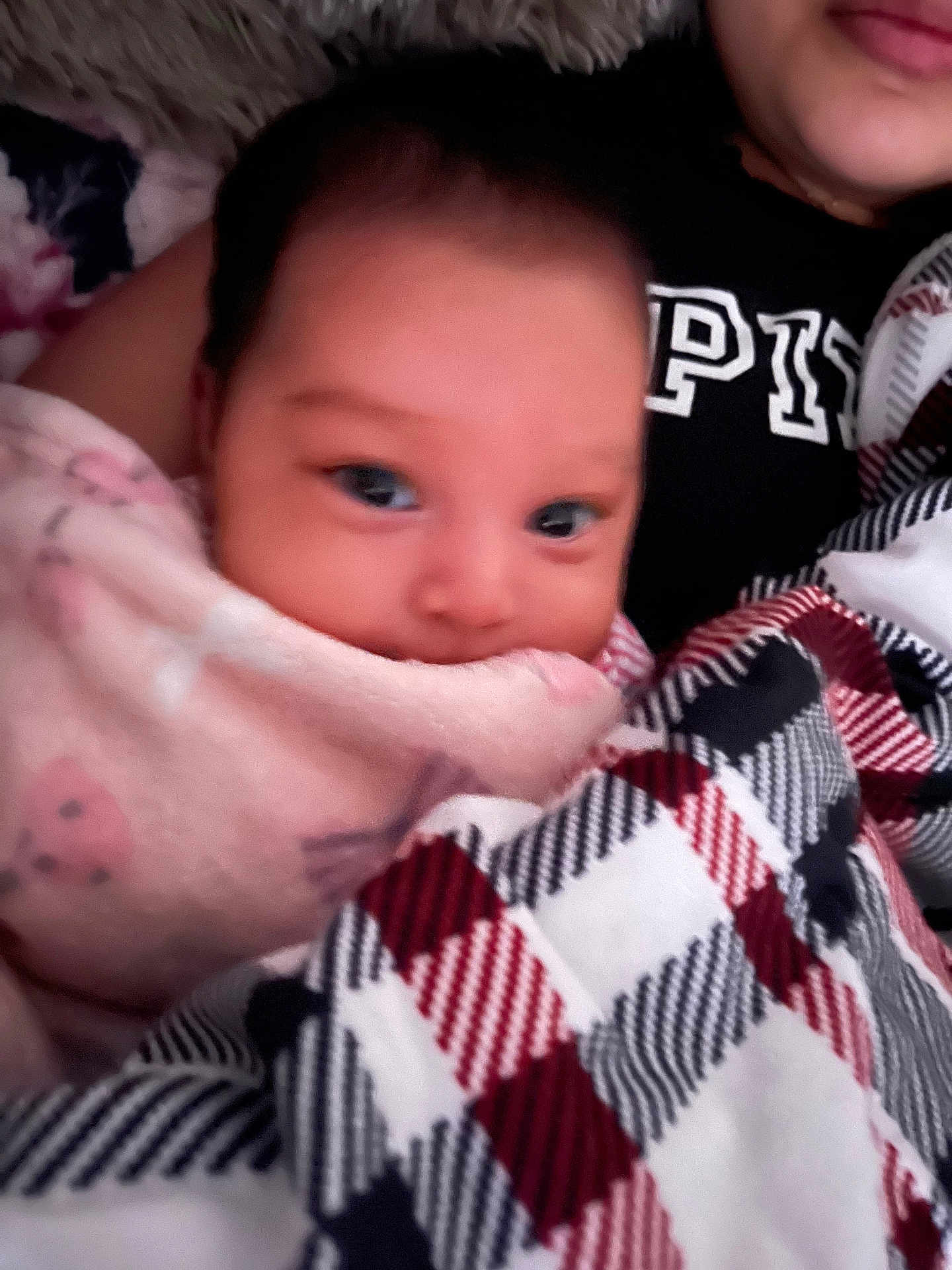 Veronica is registered to the contest to win money with this photo: baby, blanket, person, face, pink, plaid, cozy, indoor, child, clothing, black_shirt, pattern, comfort, warm, portrait, infant, snuggled, soft, young, wrapped