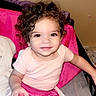 Nova joined the competition — help win amazing prizes! child, toddler, curly_hair, pink_pants, pink_shirt, smiling, indoor, bed, blanket, holding_object, person, young_child, cute, face, hair, sitting, casual_clothing, home, relaxed, portrait