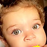 Nova joined the competition — help win amazing prizes! baby, child, face, eyes, hair, teething_toy, hand, curly_hair, close_up, indoor, portrait, cute, infant, skin, expression, top_knot, clothing, polka_dot, chewing, young