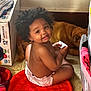 toddler, child, baby, afro_hair, smiling, sitting, diaper, red_cushion, dog, brown_dog, indoor, floor, card, box, clothing, household, pet, cute, happy, portrait