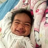 baby, smile, face, blanket, bed, cozy, happy, infant, sleepwear, dimples, child, soft, comfort, lying_down, indoors, cute, person, warm, pink, white