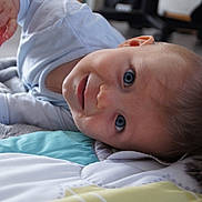 Gabriel participe au concours pour gagner de l'argent avec cette photo : baby, blanket, blue_eyes, child, closeup, clothing, curious, cute, expression, face, head, indoor, infant, laying_down, person, portrait, quilt, skin, soft_light, young_child