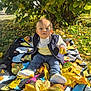 autumn, blanket, blue_eyes, child, clothing, curious, daylight, fall, grass, jacket, leaves, nature, outdoor, pants, portrait, shoes, sitting, sunlight, toddler, tree