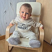 Gabriel a rejoint le concours — aidez-le/la à gagner de superbes lots ! baby, child, smiling, blue_eyes, sitting, armchair, wooden_chair, cozy, indoor, flooring, wallpaper, clothing, socks, happy, person, cute, infant, furniture, portrait, home