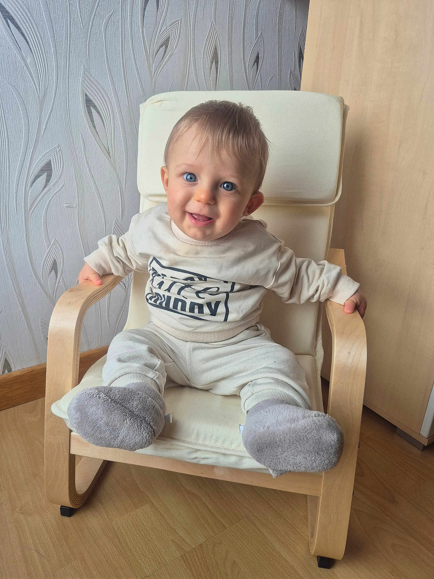Gabriel a rejoint le concours — aidez-le/la à gagner de superbes lots ! baby, child, smiling, blue_eyes, sitting, armchair, wooden_chair, cozy, indoor, flooring, wallpaper, clothing, socks, happy, person, cute, infant, furniture, portrait, home