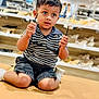 toddler, child, glasses, kneeling, cushion, bench, store, shoes, shelves, clothing, shorts, striped_shirt, indoor, footwear, curious, young_child, person, portrait, casual, shopping